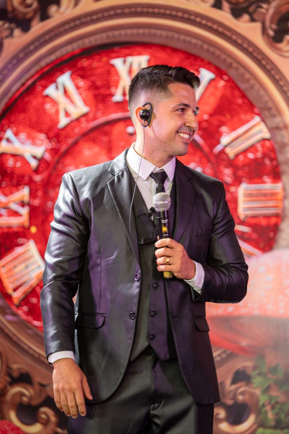 Hyago Nofre sorrindo no palco, com o relógio no punho